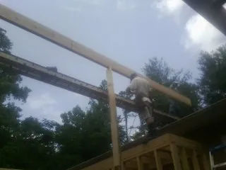 Carpenter setting a ridge beam over a new addition frame — Ice Dam Removal by Roofing Brothers in Chepachet