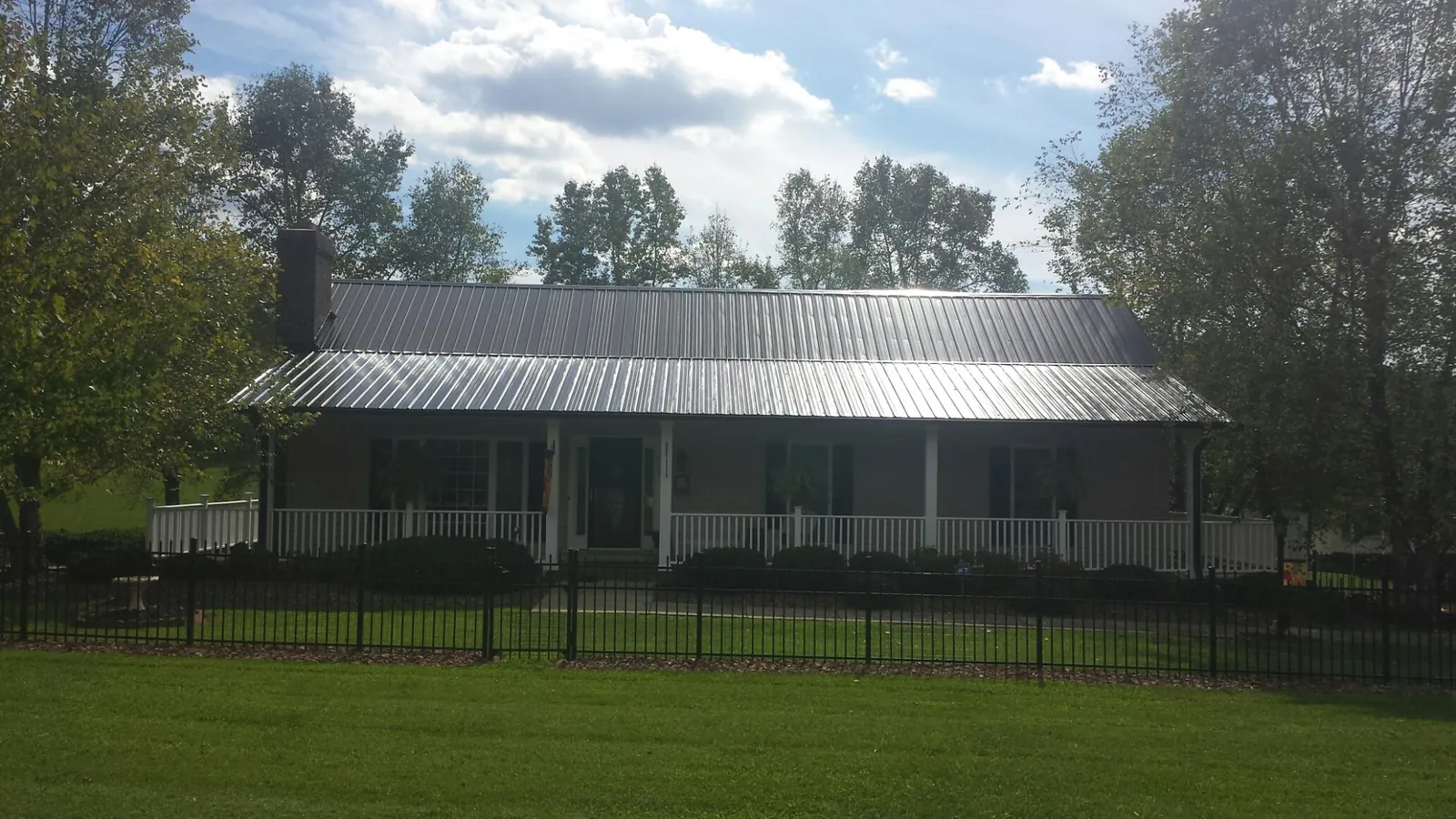Gray metal roof on a brick ranch with a full width front porch — Gutter Guard Installation work by our crew in Chepachet